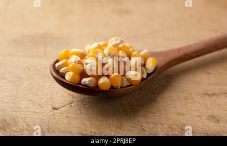 Dried corn kernels and wooden spoon placed on wooden background. Stock Photo