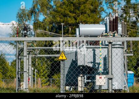High voltage electrical substation behind metal mesh fence Stock Photo