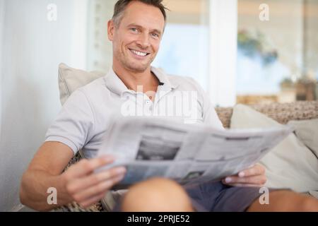 The more you read the more youll know, the more you learn more places youll go. A handsome mature man sitting comfortably at home reading the newspape Stock Photo
