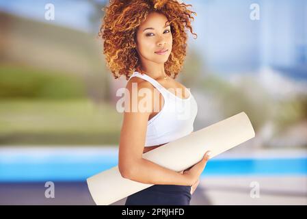 My mat is my canvas and yoga is my art. a sporty young woman holding her yoga mat. Stock Photo