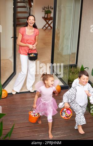 Halloween is about fun. two happy kids leaving a house on Halloween with buckets of treats Stock Photo
