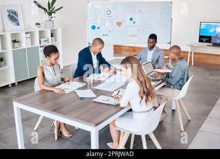 Business people working on documents and laptop at a office boardroom table. Group of professional, diversity and analysts browsing ideas online and planning and teamwork to prepare in a b2b meeting Stock Photo