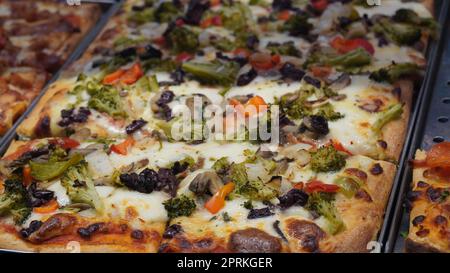 Slices of Italian pizza displayed for sale at a street food market Stock Photo