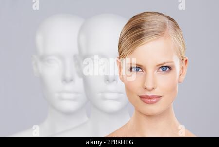 Dont be another face in the crowd. A beautiful young woman standing amongst a row of mannequins Stock Photo