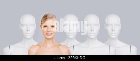 Dont be another face in the crowd. A beautiful young woman standing amongst a row of mannequins Stock Photo