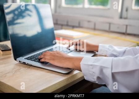 Back to school. Close up hands of female using computer sitting at school table, Young woman teacher with laptop at desk in classroom, Online educatio Stock Photo