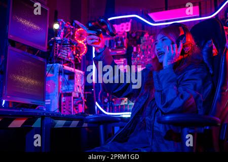 Young woman wear gaming headphones playing esports games console gaming room, Gamer using joystick controller for virtual tournament plays online vide Stock Photo