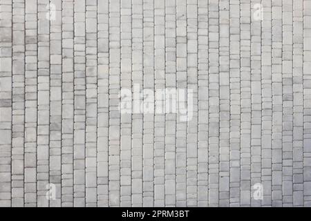 Gray color paving slabs in the pedestrian street sidewalk. Rough cobblestone pattern with many square shaped stones close up Stock Photo