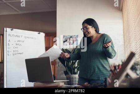 Connecting with her students from a safe distance. a young woman using a laptop to teach a lesson from home Stock Photo