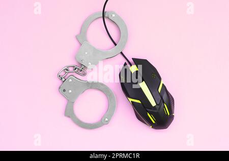 Computer mouse in a yellow color is chained in handcuffs on the background of pink color. The concept of combating computer crime, hackers and piracy. Stock Photo