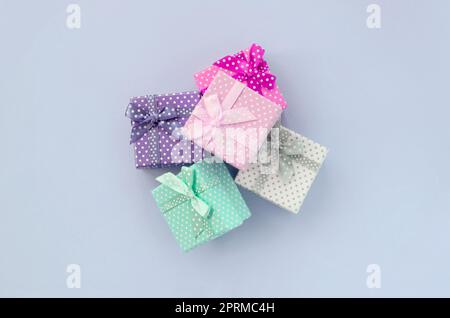 Pile of a small colored gift boxes with ribbons lies on a violet background. Minimalism flat lay top view. Stock Photo