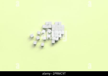 A broken heart made of sugar cubes lies on a trendy pastel lime background. Stock Photo