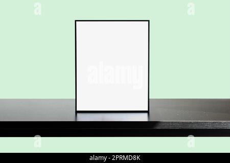Poster Frame Mockup on wooden table with Light Green wall color Stock Photo