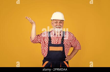 happy senior man builder in helmet on yellow background Stock Photo