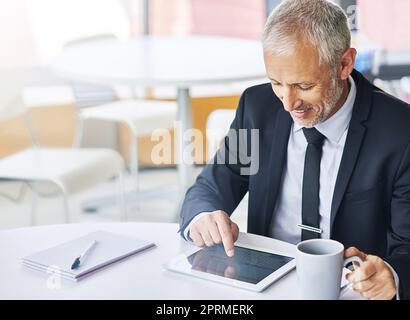Hard work is what gets you the best results. a mature businessman working on a digital tablet in an office. Stock Photo