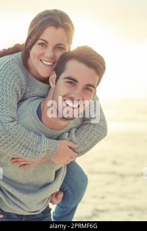 Stuck on you. Portrait of a happy young man giving his girlfriend a piggyback ride outside. Stock Photo