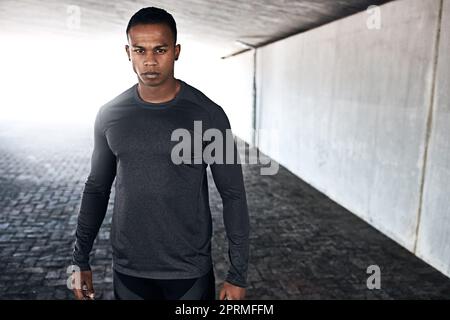 This is what determination looks like. Cropped portrait of a handsome and athletic young man standing outside while running in the city. Stock Photo