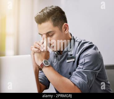 Feeling a little bit of pressure. a young man looking stressed while working on his laptop. Stock Photo