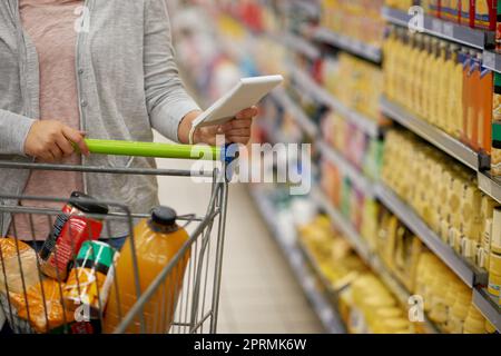 Getting all the groceries she needs. Closeup shot of a woman checking her shopping list in a grocery store. Stock Photo