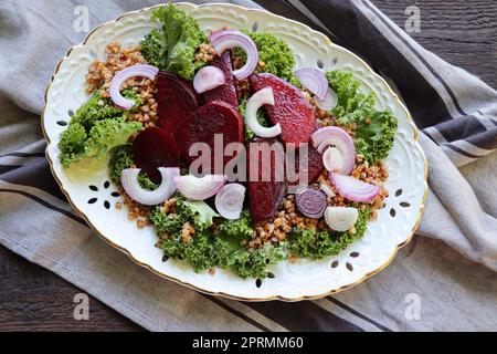 Warm buckwheat and beetroot salad on wooden background. Vegetarian diet idea and recipe -salad with beetroot, buckwheat, kale, onion, fresh herbs. Top view or flat-lay Stock Photo