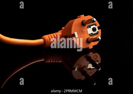 Orange electric plug on the black background. Stock Photo