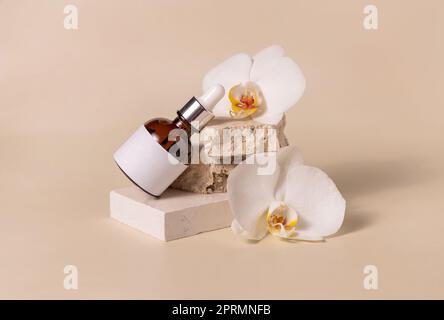 Brown dropper bottle on stone near orchid flowers on light beige, Skincare cosmetic mockup Stock Photo