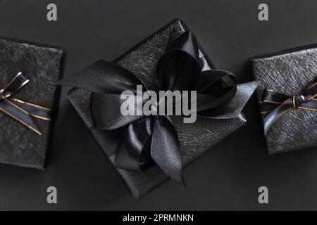 Black Gift Boxes with a ribbon bow on black top view Stock Photo