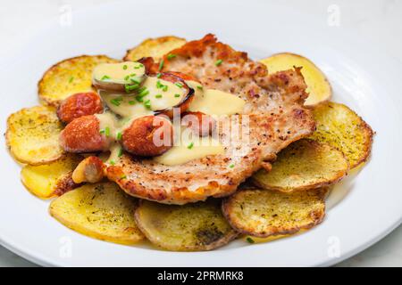 roasted pork meat with sausage, mustard sauce and roasted potatoes Stock Photo