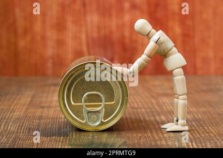 Wooden figurine of a man pushing a tin can Stock Photo