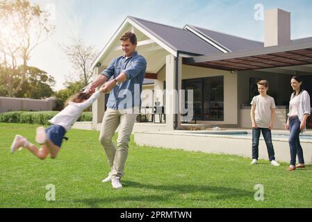 Domestic bliss at its best. a happy young family playing together in their front yard Stock Photo