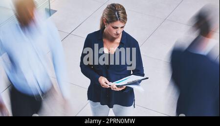 Business employee reading paperwork, crowd of people walking fast and serious corporate white woman stopping in lobby hall. Busy office building, hold company documents and people traffic blur motion Stock Photo