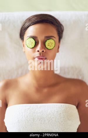 Everyone deserves a break, even your eyes do. a young woman with cucumber slices over her eyes receiving a beauty treatment at a spa. Stock Photo
