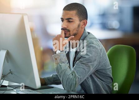 This one is a thinker...a young designer deep in thought while working on a computer in a modern office. Stock Photo