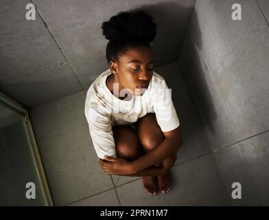 Depression, anxiety and sad girl with mental health problem sitting alone in shower thinking while feeling emotional. Stress, fail and mistake in toxic relationship after suffering abuse and stress Stock Photo