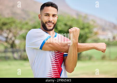 Fitness, portrait and soccer player stretching in training, workout and warm up exercise on a soccer field. Smile, healthy and happy sports man ready Stock Photo