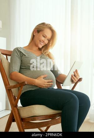 Creating my own pregnancy slideshow. a pregnant woman using her digital tablet while sitting on a rocking chair Stock Photo