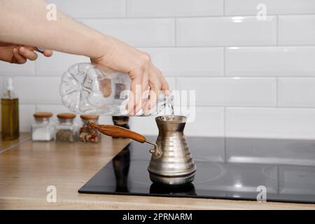 Man makes coffee in cezve, pouring pure water Stock Photo