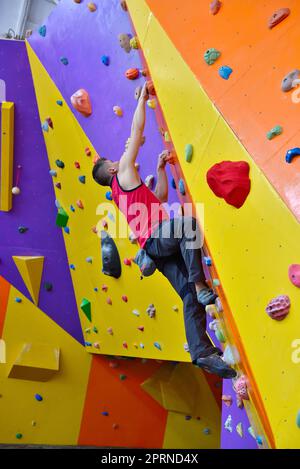 Free Climber Man Climbing On Color Practice Wall Indoors Stock Photo