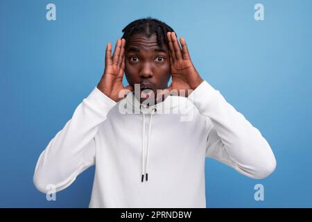 Energetic dark-skinned young brunette male tries to scare Stock Photo
