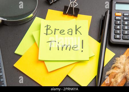 bottom close view break time written on sticky note colorful sticky notes lupa pen calculator cinnamon sticks ruler on dark background Stock Photo