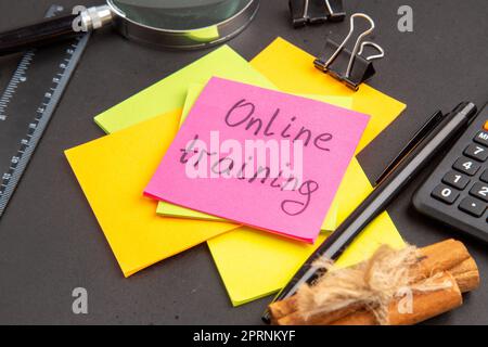 bottom close view online training written on sticky note colorful sticky notes lupa pen calculator cinnamon sticks ruler on dark background Stock Photo