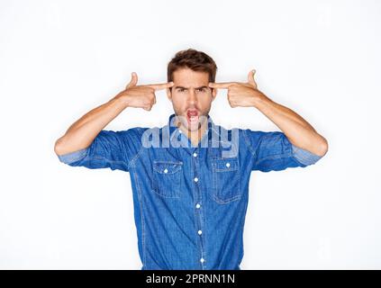 Ive had enough. Handsome young man putting his fingers to his head in a gun gesture Stock Photo