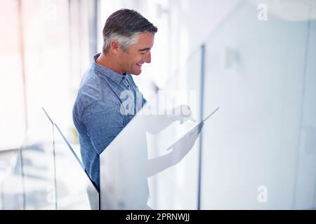 Handling his business on the go. a mature businessman using a digital tablet on the stairs in a modern office. Stock Photo