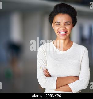 Shes the embodiment of job satisfaction. Cropped portrait of a young businesswoman standing with her arms folded in the office. Stock Photo