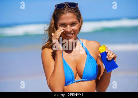 Ive gotta look after my skin. a beautiful young woman at the beach. Stock Photo