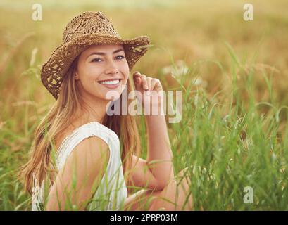 Breathe the fresh air of the countryside. a young woman sitting in a field in the countryside. Stock Photo