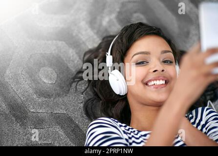 Life is one sweet melody. a young woman listening to music at home. Stock Photo