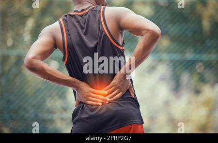 Athletic, fit man with lower back pain, outdoors hold and massages tired and strain muscles or spinal injury. Muscular black man with cramps, inflammation or burning and sore muscle seeking relief. Stock Photo