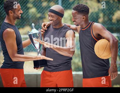 Award, success and basketball athletes with a trophy as a reward or prize after winning a competitive sports game. Challenge, fitness and happy African winners in celebration after mens championship Stock Photo