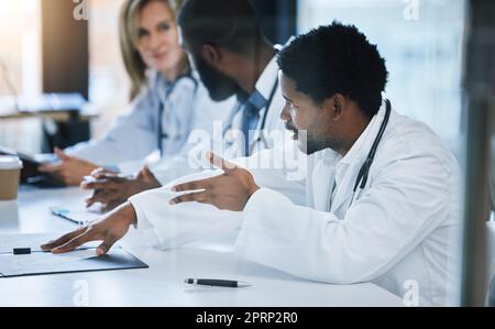 Healthcare, diversity and a medical conference, male doctor in discussion or meeting with team. Teamwork, collaboration and communication, health care workers talking and planning at hospital office. Stock Photo